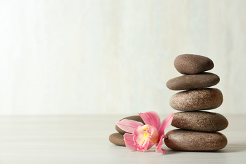 Fototapeta na wymiar Stack of spa stones and flower on table against white background, space for text