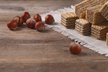 Delicious wafers with hazelnuts on brown wooden background. Space for text