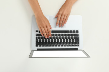 Fototapeta na wymiar Woman using modern laptop on light background, top view