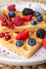 Delicious waffles with fresh berries served on table, closeup