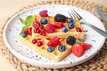Delicious waffles with fresh berries served on white wooden board