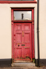 A red door with a transom window along a street in Ireland