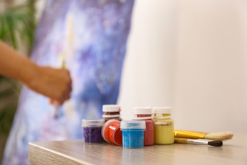 Jars with colorful paints on wooden table indoors, space for text. Interior design