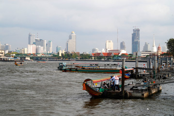 skyline of Bangkok at the Chao Phraya river with traditional boats