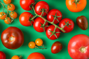 Flat lay composition with fresh ripe tomatoes on green background