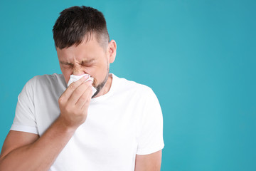 Man suffering from allergy on blue background. Space for text