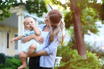 Teen nanny with cute baby outdoors on sunny day