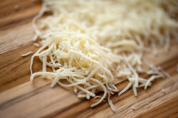 Shredded white cheese on rustic wooden cutting board