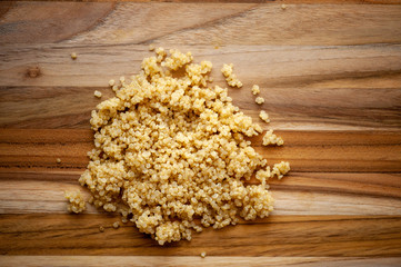 Pile of cooked quinoa on rustic wooden cutting board