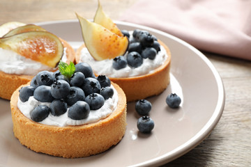 Plate of tarts with blueberries and figs on wooden table, closeup. Delicious pastries