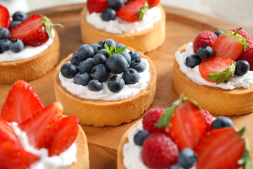 Wooden plate with different berry tarts. Delicious pastries