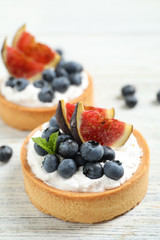 Tarts with blueberries and figs on white wooden table. Delicious pastries