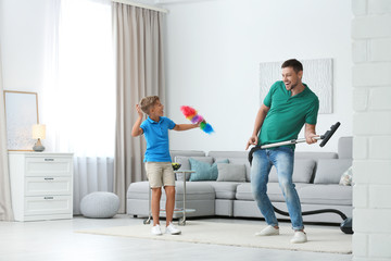 Dad and son having fun while cleaning living room together