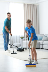 Dad and son cleaning living room together