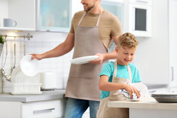 Dad and son wiping dishes in kitchen