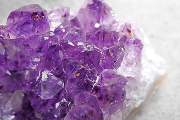 Fototapeta premium Beautiful purple amethyst gemstone on grey table, closeup