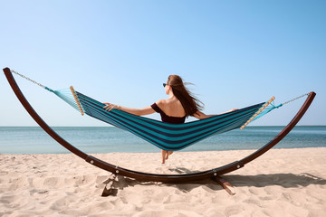 Fototapeta premium Young woman relaxing in hammock on beach