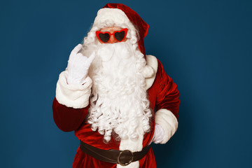 Fototapeta na wymiar Authentic Santa Claus wearing sunglasses on blue background