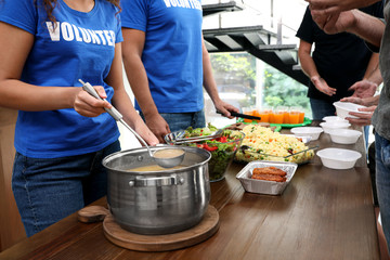 Volunteers serving food to poor people in charity centre, closeup
