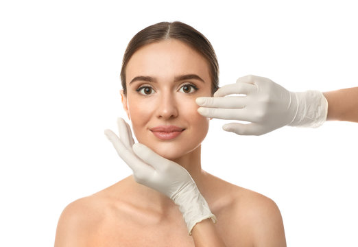 Doctor examining woman's face before plastic surgery on white background - Powered by Adobe