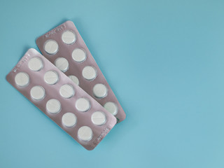 The concept of medicine and healthcare. Blisters of white pills on a blue background, top view, placeholder.