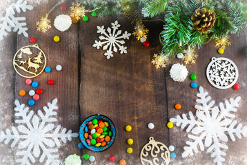 Merry Christmas and happy New year. Christmas decoration design on wooden background with candy bowl.the composition of Christmas tree branches, lights, cones, toys, candy, snowflakes.