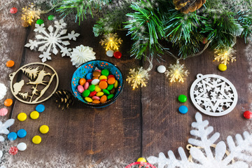 Merry Christmas and happy New year. Christmas decoration design on wooden background with candy bowl.the composition of Christmas tree branches, lights, cones, toys, candy, snowflakes.