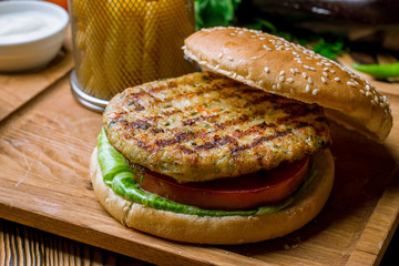 Burger with chicken and fries with sause on the board