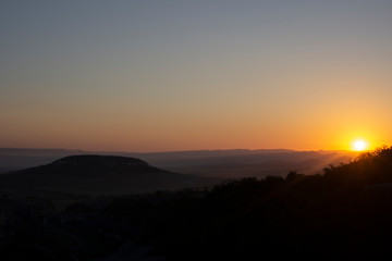 Fototapeta premium Dawn in the mountains. Mountain landscape. The sun rises from the horizon. Beautiful background early hours in the highlands. Bright rays shine from afar.