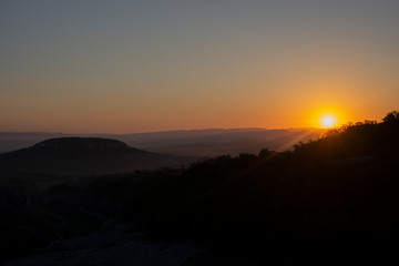 Dawn in the mountains. Mountain landscape. The sun rises from the horizon. Beautiful background early hours in the highlands. Bright rays shine from afar.