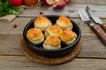 mushrooms baked with Suluguni cheese on old wooden table