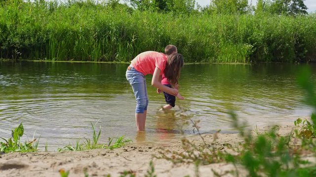 children looking for snails in the shallow river