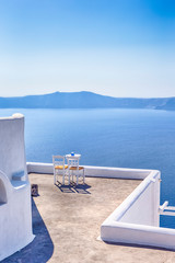 Fototapeta na wymiar Pair of White Chairs on The Edge of The Roof in Thira City of Santorini.