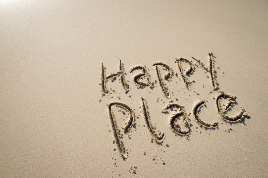 Happy Place tropical vacation message handwritten on smooth sand beach