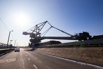 Fototapeta na wymiar Stacker-reclaimer during loading and unloading of coal. Coal heaps at a marine coal terminal