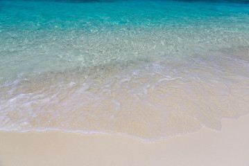 Ocean wave on a tropical paradise sandy beach. Beautiful surface texture, travel landscape clean white sand and blue turquoise sea water, wave ripple in beautiful ocean and natural sandy island.