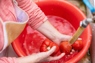 Woman washing organic homegrown tomatoes in kitchen sink. Slow motion . 