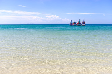 Fishing boat floating on tropical blue turquoise crystal clear water, white sand beach and lush green mountain at Chaloklum beach in Phangan Island. Surat Thani, Gulf ofThailand