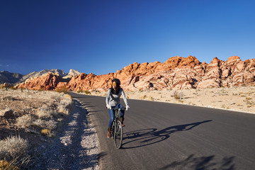 Fototapeta premium african american woman riding bicycle through red rock canyon park