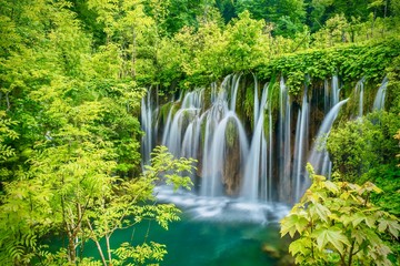 Beautiful silky waterfalls dropping into an emerald green pool, surrounded by lush vegetation.