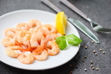 shrimps served on plate with Lemon, Herb, Pepper on white plate - boiled peeled shrimp prawns cooked in the restaurant