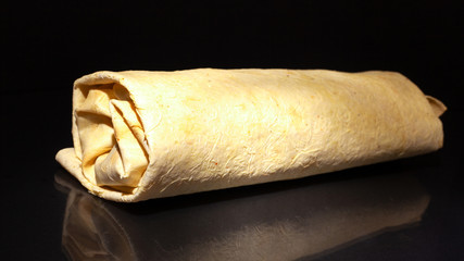 shawarma wrapped in pita bread on a dark background
