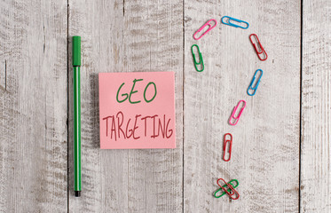 Word writing text Geo Targeting. Business photo showcasing Digital Ads Views IP Address Adwords Campaigns Location Pastel colour note paper placed next to stationary above the wooden table