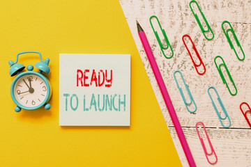 Handwriting text Ready To Launch. Conceptual photo an event to celebrate or introduce something new to market Notepad marker pen colored paper sheet clips alarm clock wooden background