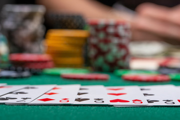 Fototapeta premium Close-up cards for playing poker on a gaming table in a casino against a background of chips. Background for a gaming business
