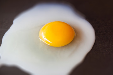 Egg fried in a frying pan. On a black hot iron pan fried chicken egg, yolk and protein. The morning Breakfast is a delicious meal.