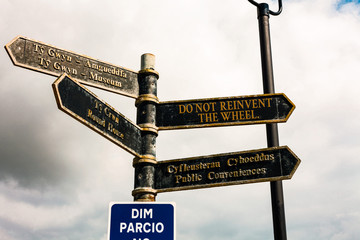 Writing note showing Do Not Reinvent The Wheel. Business concept for stop duplicating a basic method previously done Road sign on the crossroads with blue cloudy sky in the background