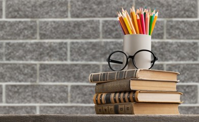 Stack of vintage books, eyeglasses and pencils, education and learning