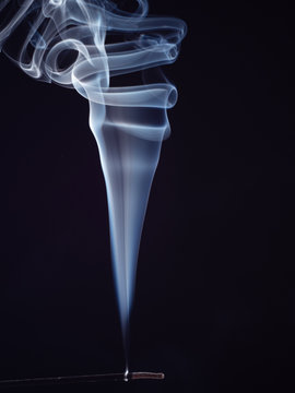 White smoke from burning incense isolated on black background, close up view. Abstract background, smoke brush. Eastern sweet smell for meditation. Fragrance for relaxation
