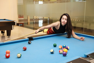 Fototapeta premium young beautiful asian woman playing and aiming for billiards ball on blue pool table in club